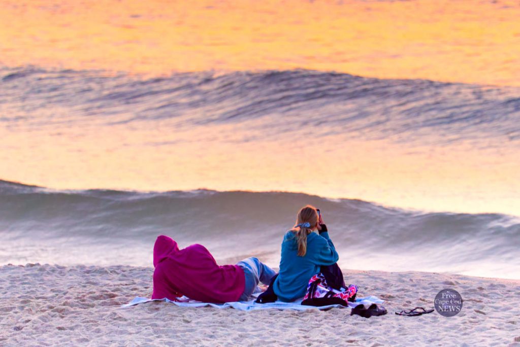 Cape Cod Weather tonight - July 31, 2020. Free Cape Cod News - Photo: Couple watching sunset on Cape Cod beach.