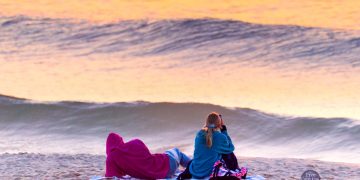 Cape Cod Weather tonight - July 31, 2020. Free Cape Cod News - Photo: Couple watching sunset on Cape Cod beach.